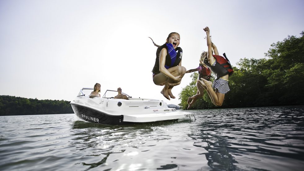 Kids jumping off the swim platform of a Bayliner sport boat