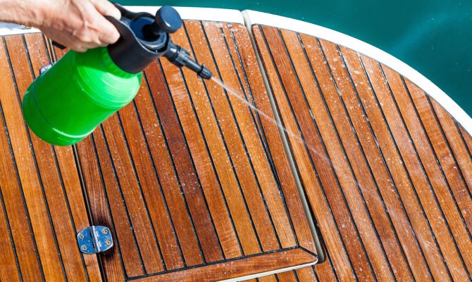 Spraying cleaning solution on deck of boat.
