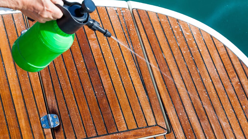 Spraying cleaning solution on deck of boat.
