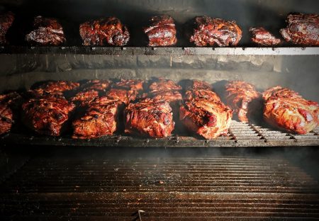 Pork being barbequed in a southern style pit over hickory wood.